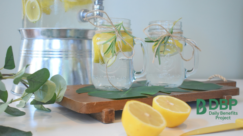 Two jars of lemon water with rosemary on a wooden board