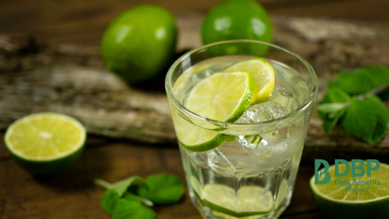 A clear glass with lime slices and mint on a rustic table