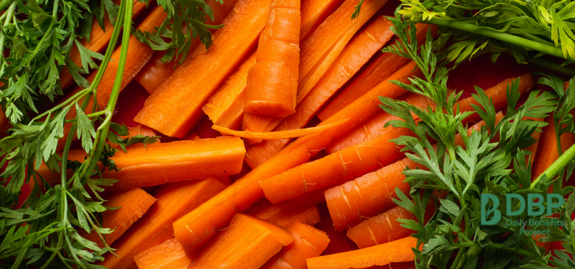 Fresh Sliced Carrots on Wooden Surface Freshly sliced carrots with green tops