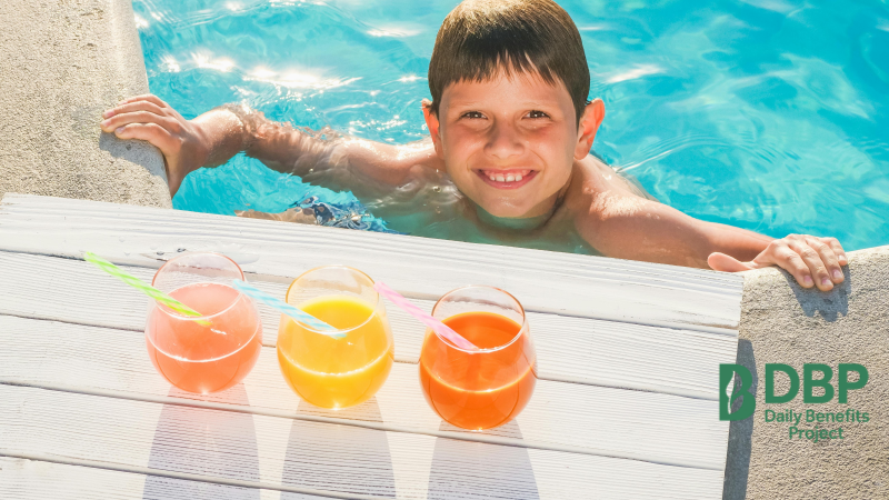 Smiling Kid with Colorful Drinks by the Pool A happy child in a pool with three colorful drinks on the poolside