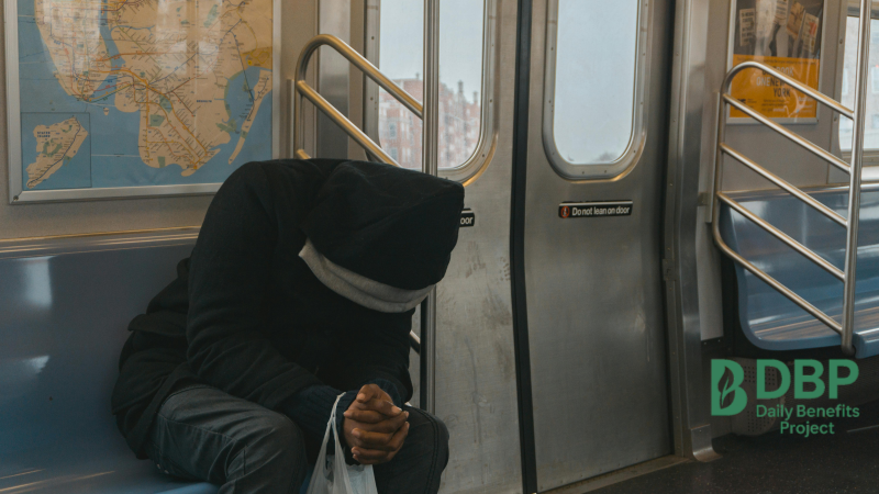 Man slouched and sleeping on subway train Person sleeping with head down on public transport seat, wearing hoodie
