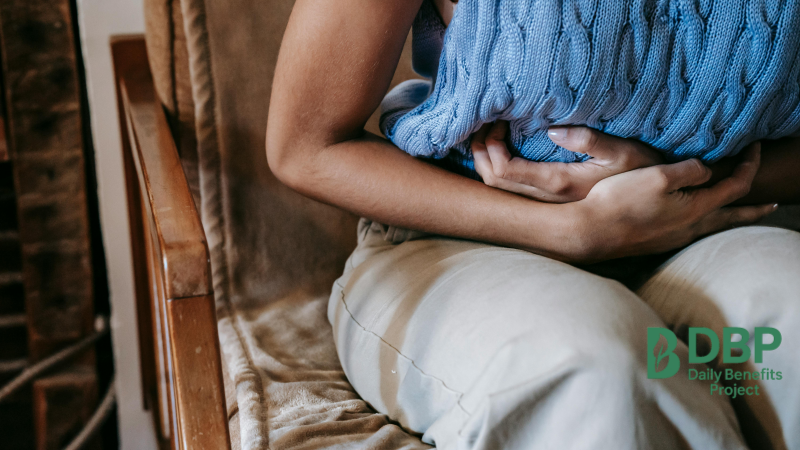 Woman holding stomach in discomfort Close-up of woman holding belly while sitting with hot pack